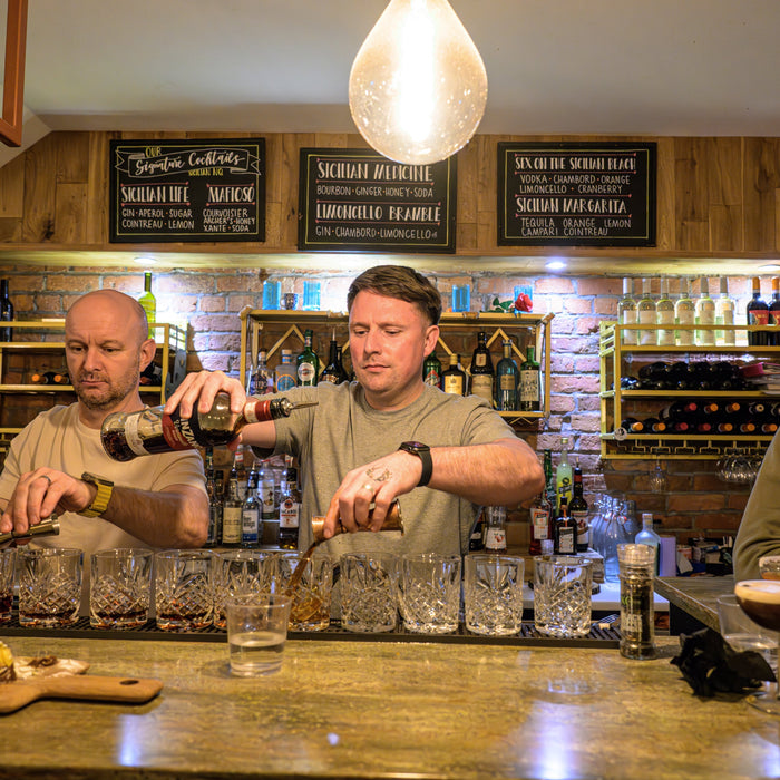	Corporate group celebrating with a Christmas cocktail masterclass, smiling and mixing cocktails behind the bar