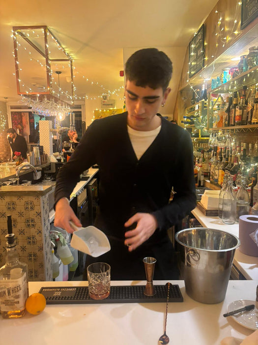 Student practising cocktail service techniques behind the bar at Dirextra
