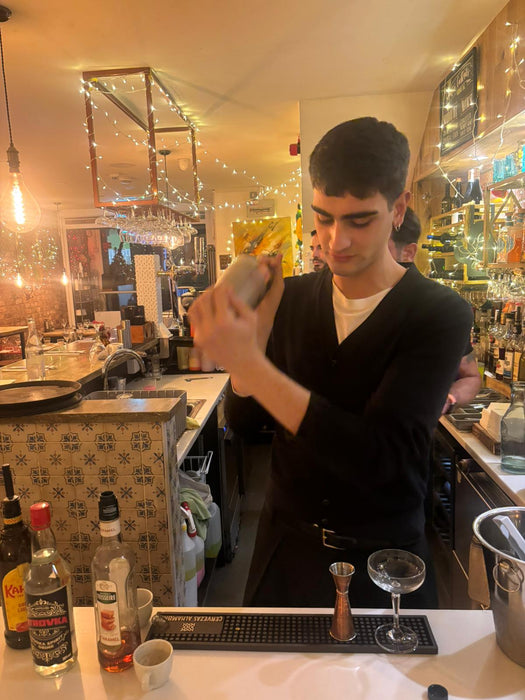 Hands-on cocktail shaking practice with a participant using professional bar tools